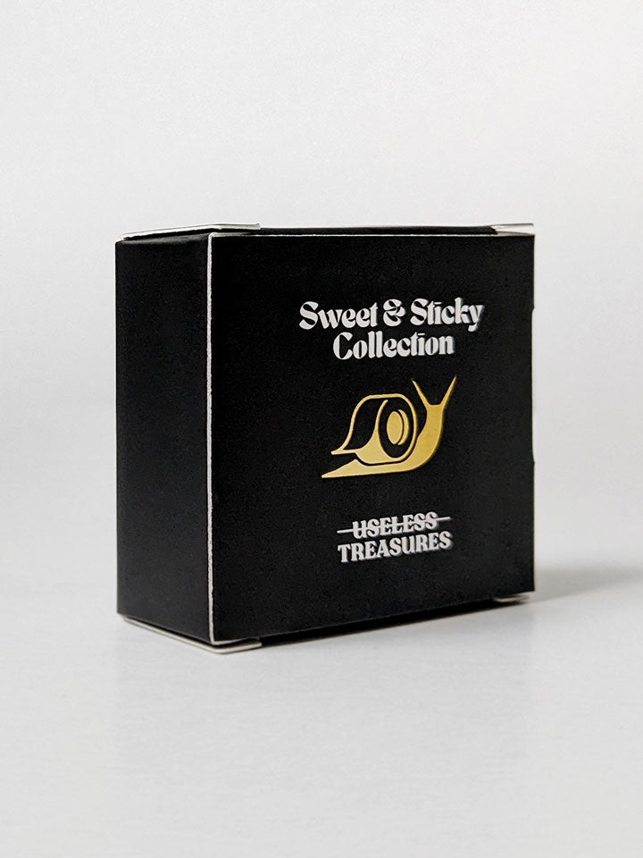 A black cardboard box with gold details and a snail icon - an original package of useless treasures illustrated washi tape. 